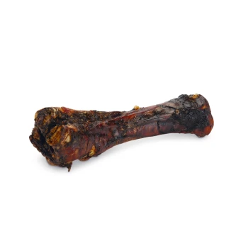 Duża, mięsista kość dla psa z ciemną, przypaloną powierzchnią, prezentująca bogatą, soczystą teksturę idealną do żucia.