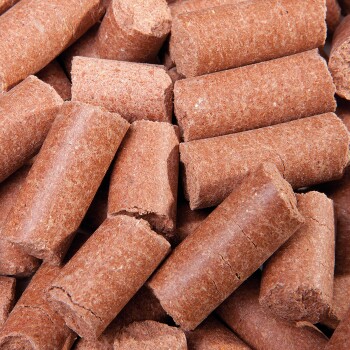 Nahaufnahme von braunen Tierfutterpellets, zylindrisch geformt, mit einer rauen Textur, die in einem Haufen verstreut sind.