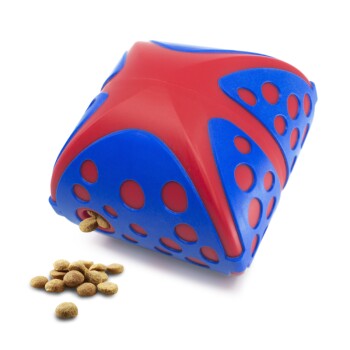 Jouet distributeur de friandises pour animaux en forme d'étoile rouge et bleue avec plusieurs trous et des croquettes qui débordent d'une ouverture.