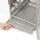 Eine Hand zieht eine Schublade aus einem grauen Metall-Haustierkäfig, der eine Edelstahl-Futterschüssel an der Seite hat.