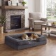 Beagle schläft auf einem grauen, rechteckigen Hundebett mit Rand in einem Wohnzimmer mit Steinkamin, Sessel und Couchtisch.