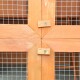 Nahaufnahme einer Ecke eines Holzhaustiers, die ein Gitterdrahtgeflecht und mit Schrauben gesicherte Holzstützen zeigt.