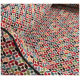 Buntes Haustierbett mit geometrischem Muster, das rote, grüne, blaue und schwarze Formen auf einem cremefarbenen Hintergrund zeigt.