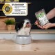 Schwarz-weißer Hund frisst einen Löffel verpacktes Rohfutter mit der Aufschrift "COMPLETE"; DLG-Qualitätssiegel und deutscher Text sichtbar.