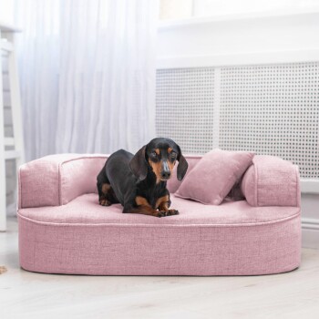 Eine Nahaufnahme eines weichen rosa Haustierbettes mit einem plüschigen Kissen und einer abgerundeten Armlehne, die einen strukturierten Stoff zeigt.