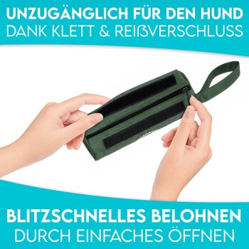 Eine grüne Hundeleckerlitasche, die von zwei Händen gehalten wird, mit Klettverschluss und Reißverschluss; der Text sagt "UNZUGÄNGLICH FÜR DEN HUND" und "BLITZSCHNELLES BELOHNEN".