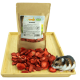 Ein kleiner Hamster sitzt neben einem Beutel mit getrockneten Erdbeeren, der mit "GETZOO 100% FRESH" beschriftet ist, auf einem Holztablett, mit Erdbeerscheiben, die herumliegen.