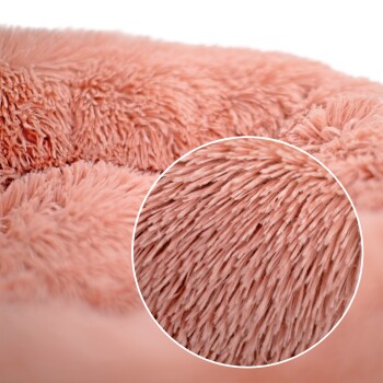 Nahaufnahme eines weichen, plüschigen Haustierbettes in hellrosa, das seine flauschige Textur und gemütliches Design zeigt.