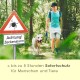 Ein Mann führt einen Hund auf einem Waldweg in der Nähe eines Zeckenwarnschildes mit der Aufschrift "Achtung! Zeckenalarm." Darunter: "bis zu 5 Stunden Sofortschutz."