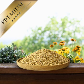 Eine Holzschüssel mit Vogelfutter auf einer Holzoberfläche, umgeben von grünen Pflanzen und gelben Blumen, mit einem goldenen "PREMIUM"-Label.