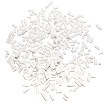 Ein verstreuter Haufen kleiner, weißer zylindrischer Pellets, die Haustierfutter oder Nahrungsergänzungsmittel ähneln, vor einem schwarzen Hintergrund.