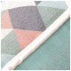 Gros plan d'une couverture pour animaux de compagnie confortable avec un motif géométrique en couleurs pastel, y compris le rose, le gris, le vert et le bleu.