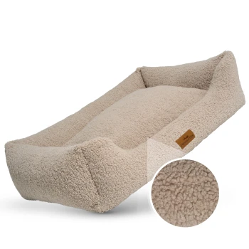 Ein gemütliches beiges Haustierbett mit erhöhten Rändern und einer weichen, flauschigen Textur, mit einem kleinen braunen Etikett, das "FRENCHIE TAILS" liest.