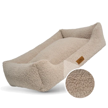 Ein gemütliches beiges Haustierbett mit erhöhten Rändern und einer weichen, flauschigen Textur, mit einem kleinen braunen Etikett, das "FRENCHIE TAILS" liest.