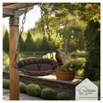 Hängendes Vogelbad mit einer dekorativen Vogelfigur, in einem üppigen Garten mit Grünpflanzen und einem Weidenkorb im Hintergrund.