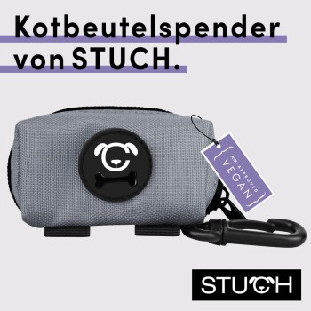 Grauer Hundekotbeutelspender mit einem schwarzen Hundelogo, mit einem Etikett, das 'Ich bin genehmigt vegan' liest und dem Markennamen STUCH.