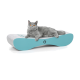 Eine graue Katze mit orangefarbenen Augen, die auf einem modernen, türkisfarbenen und grauen Haustierbett entspannt.