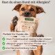 Eine Person kniet auf einem blattbedeckten Weg und füttert einen goldenen Hund aus einer Tüte, die mit "Optimal für Allergiker" und verschiedenen Gesundheitsansprüchen beschriftet ist.
