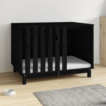 Schwarze Holzhaustierbox mit lamellenförmigen Seiten und einem weißen Kissen innen, auf einem hellen Holzboden neben einem grauen Teppich und einer weißen Futterschale platziert.