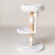 Ein stilvoller weißer Kratzbaum für Katzen mit zwei plüschigen Plattformen, natürlichen Holzpfosten und einem Seilkratzbereich, vor einem neutralen Hintergrund.