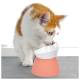 Eine neugierige orange-weiße Katze lehnt sich zu einer modernen pink-weißen Futterschüssel, die anscheinend daraus trinkt.