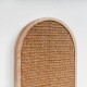 Eine Nahaufnahme eines natürlichen, gewebten Kratzbaums mit einem runden Holzrahmen, vor einer weißen Wand.