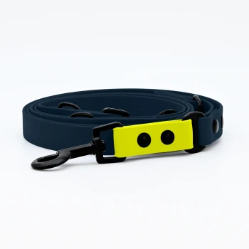 Biothane Hundeleine Navy Eine marineblaue Hundeleine mit einem hellgelben Griff, der schwarze Knöpfe und einen stabilen Clip am Ende hat.