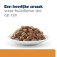 Een witte kom gevuld met bruine hondenvoerbrokjes, met de tekst "Een heerlijke smaak waar huisdieren dol op zijn" erboven.