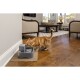 Un chat tigré orange joueur boit dans une fontaine à eau pour animaux moderne grise placée sur un tapis tissé dans un cadre de salon confortable.