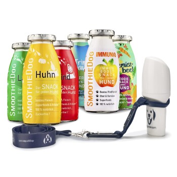 Eine Sammlung von bunten Smoothie-Flaschen für Hunde mit der Aufschrift "SmoothieDog", die Geschmäcker wie Huhn, Rind und Gemüse enthalten, neben einer Hundeleine.