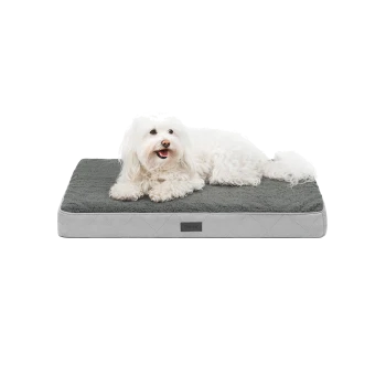 Ein flauschiger weißer Hund liegt bequem auf einem grauen Haustierbett mit einem gesteppten Design, das eine weiche, plüschige Oberfläche hat.