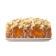 Ein Stück Haustierfutterlaib mit Stücken von orangefarbenen Karotten, bedeckt mit einer cremigen Schicht, präsentiert auf einem weißen Teller.