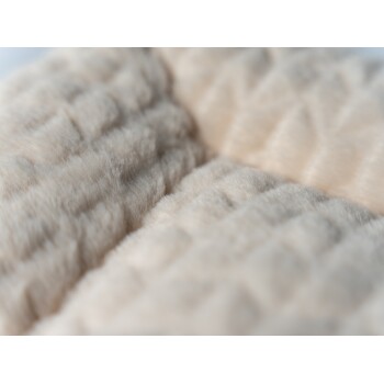 Nahaufnahme eines weichen, beigen Haustierbettes mit einer strukturierten, gesteppten Oberfläche, ideal für den Komfort von Haustieren.