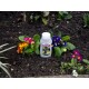 Bottle of 'GETOFF' cat repellent (label: Cat Repellent, GET OFF) placed among colorful primrose flowers in garden soil.