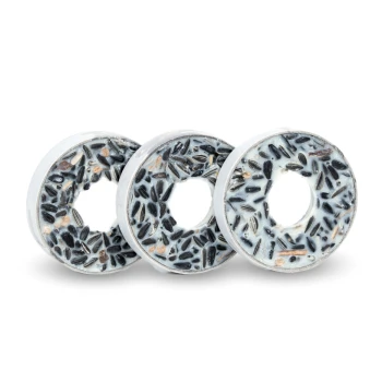 Drei kreisförmige Vogelfutter-Donuts mit einer Mischung aus schwarzen Samen und einer weißen äußeren Schicht, in einer Reihe auf einem weißen Hintergrund angeordnet.