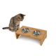 Getigerte Katze sitzt neben einem erhöhten doppelten Bambus-Futterspender mit zwei Edelstahlschalen und 'lionto'-Logo.