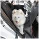Ein flauschiger weißer Samojede-Hund entspannt sich auf dem Rücksitz eines Autos, umgeben von einem schwarzen Autositzbezug.