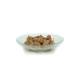 Ein Glasgericht mit feuchtem Haustierfutter, das Fleischstücke gemischt mit kleinen Gemüsestücken enthält, vor einem weißen Hintergrund.