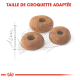 Trois croquettes de nourriture pour animaux de compagnie rondes avec un trou au centre, présentées sur un croquis de mesure léger, avec le texte "TAILLE DE CROQUETTE ADAPTÉE" au-dessus.