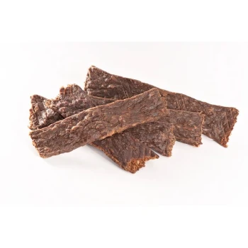 Ein Haufen dunkler, zäher Tierleckerlis, die Jerky-Streifen ähneln, auf einem weißen Hintergrund angeordnet.