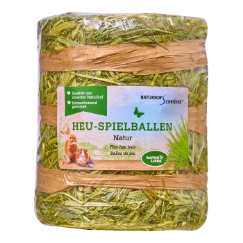 Ein verpackter Spiel-Heuballen mit der Aufschrift "HEU-SPIELBALLEN Natur" mit Bildern von Kaninchen und kleinen Tieren, mit grünem Gras und natürlichen Fasern.