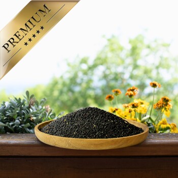 Eine Holzschale mit schwarzen Samen auf einer Holzoberfläche, umgeben von grünen Pflanzen und gelben Blumen, mit einem goldenen Banner "PREMIUM."