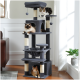 Drei Katzen entspannen sich auf einem mehrstöckigen grauen Katzenbaum mit Kratzpfosten und hängenden Spielzeugen, in einem hellen Raum mit einer Pflanze.