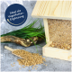 Holz-Vogelfutterspender gefüllt mit Samen, mit verschütteten Samen auf dem Boden und grünem Gras im Hintergrund. Text: "Ideal als Vogelfutter-Ergänzung."