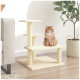 Eine flauschige orange Katze sitzt auf einem beigen Katzenbaum mit drei Ebenen, neben einer Topfpflanze und einem hellgrauen Sofa.
