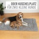 Zwei kleine Hunde ruhen auf einem weichen grauen Haustierbett, mit dem Text darüber 'oder Kuschelplatz für zwei kleine Hunde.'