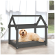 Ein Golden Retriever, der bequem auf einem grauen Haustierbett in einem Holz-Hundehäuschen mit schrägem Dach liegt, das sich in einem hellen Raum befindet.