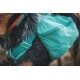 Eine Nahaufnahme eines Hundegeschirrs mit einem türkisfarbenen Rucksack, das das Fell des Hundes und die verstellbaren Riemen des Geschirrs zeigt.