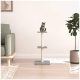 Eine getigerte Katze sitzt auf einem dreistufigen Kratzbaum in einem modernen Wohnzimmer, neben einer grünen Pflanze und einem gemütlichen Sofa.