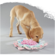 Golden Labrador puppy sniffing a pastel pink, blue and mint fabric snuffle mat toy on gray background.